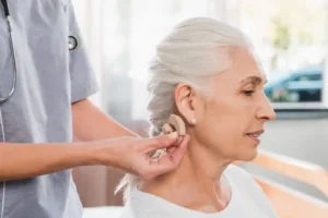 Nurse helping an older patient with a hearing aid