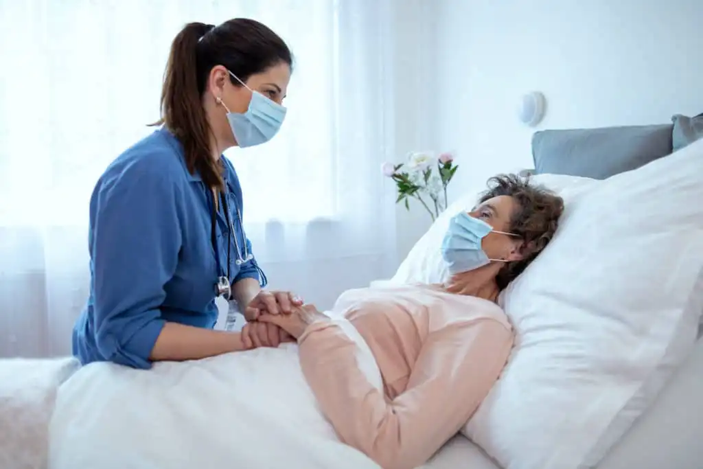 Home caregiver providing comfort care to an elderly female patient at home