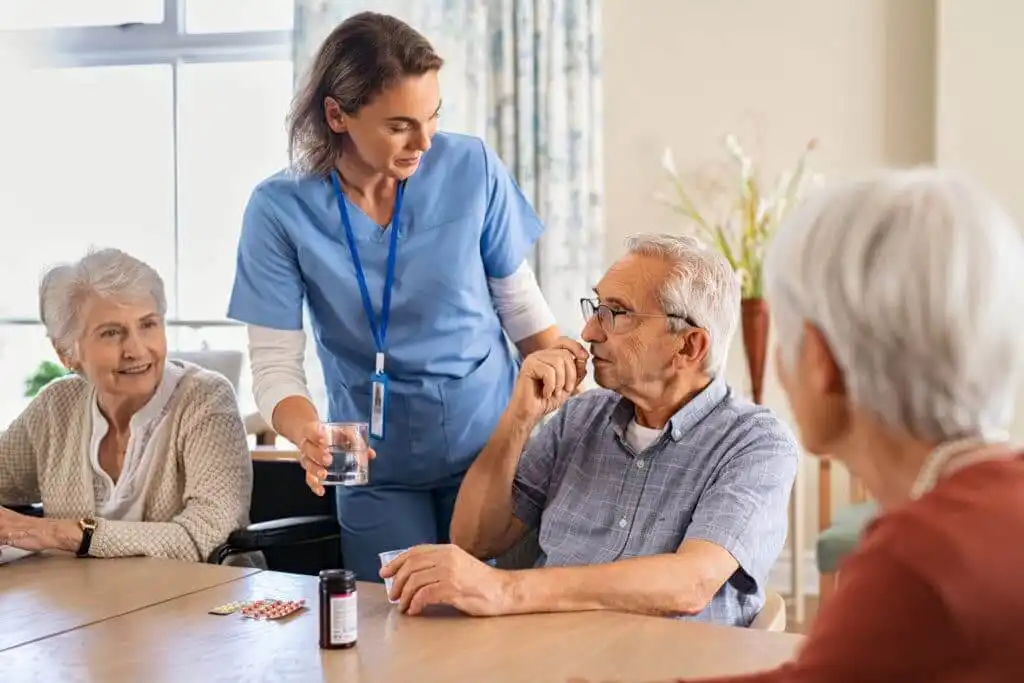 Nurse helping a senior man take daily medication at home, illustrating what services hospice provides for comfort and care.