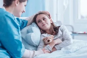 A compassionate hospice nurse comforting a young child in a cozy, child-friendly hospice room, with the child’s family nearby.